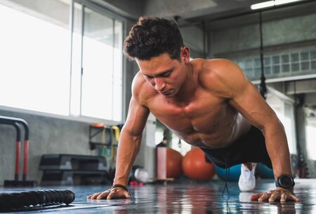Fitness man doing push up in gym. Exercise and workout concept.の写真素材