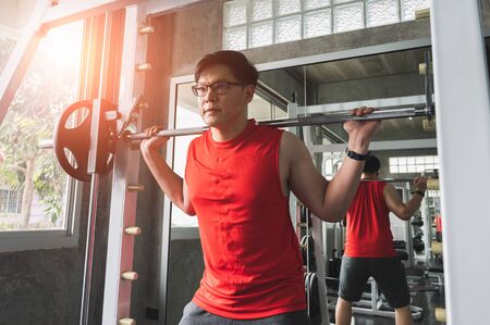 Strong muscular asian man workout in gym doing exercises at biceps.  Weight training concept.の写真素材
