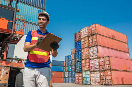 Foreman holding clipboard working at Container cargo harbor. Business Logistics import export...