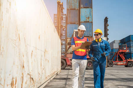 Foreman and dock worker staff working checking at Container cargo harbor holding clipboard. Business...