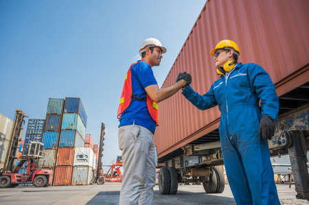 Foreman and dock worker staff shaking hand for sucess working at Container cargo harbor. Business Logistics import export shipping concept.の写真素材