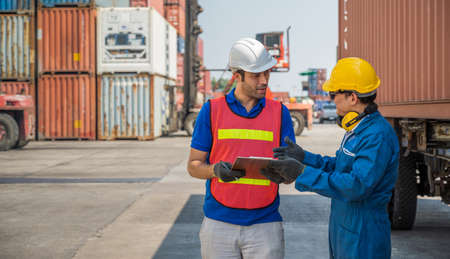 Foreman and dock worker staff working checking at Container cargo harbor holding clipboard. Business Logistics import export shipping concept.の写真素材