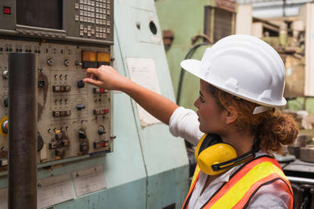 Female industrial worker working and checking machine in a large industrial factory with many equipment.の写真素材