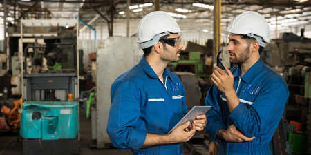 Industrial workers are working on projects in large industrial plants with many devices.