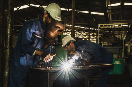 Industrial worker welding metal with many sharp sparks