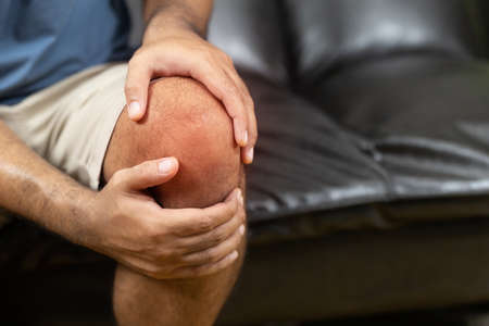Men have rheumatoid arthritis. He has a knee pain. With both hands to hold the kneeの写真素材