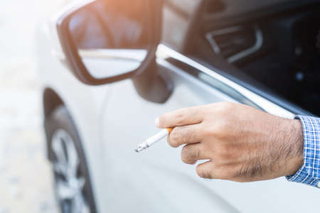 Young man smoking a cigarette in car.の写真素材
