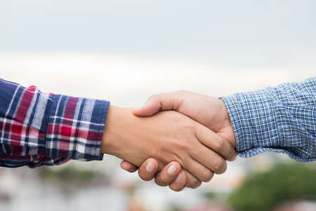 Two men shaking hands to dealing success agreement business. Business people wearing scott shirt on...