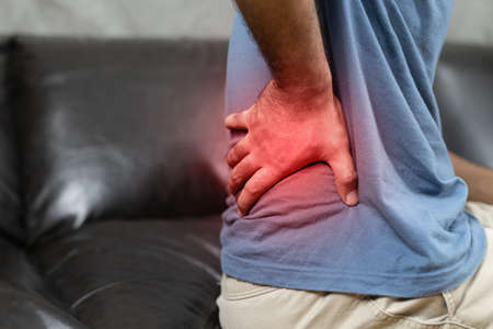 Man suffering from back pain on the sofa at home