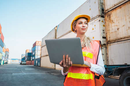 Foreman woman worker working checking at Container cargo harbor holding laptop computer to loading...
