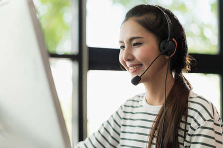 Young business asian woman working call centre customer service agents. Business female support operator with computer and headset in office.の写真素材