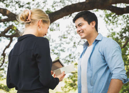 Young couple lovers giving a gift box in the park Romantically.