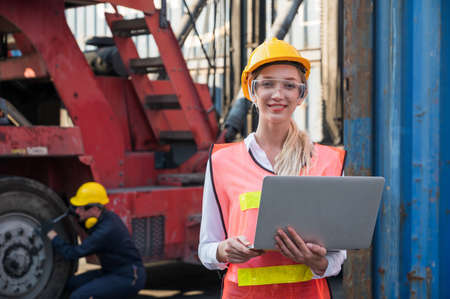 Foreman woman and worker man operate checking the forklift container cargo harbor holding laptop computer.の写真素材