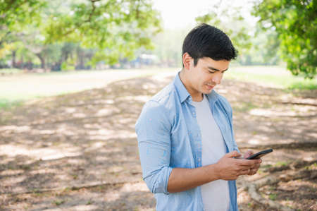 Young businessman caucasian, white using smartphone while walking in the park.