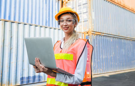 Foreman woman worker working checking at Container cargo harbor holding laptop computer to loading containers. Dock female staff business Logistics import export shipping concept.の写真素材