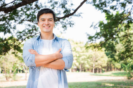 Young handsome caucasian, white smiling standing with arms crossed in the park. Portrait of cheerful...
