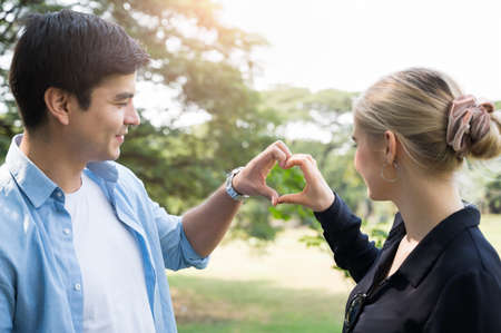 Young couple lovers doing love sign in the park Romanticly. On a relaxing holiday.の写真素材