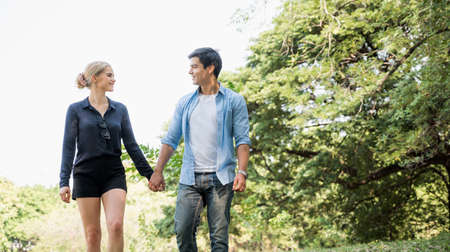 Young lovers walk hand in hand in the park Romanticly. On a relaxing holiday