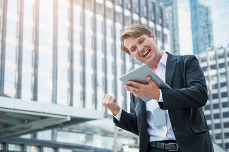 Young business man feeling happy celebration with hand and holding tabletの写真素材