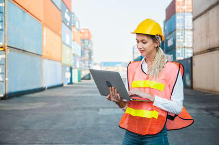 Foreman woman worker working checking at Container cargo harbor holding laptop computer to loading containers. Dock female staff business Logistics import export shipping concept.の写真素材