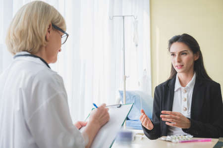Senior female doctor meet the patient discussing and making notes about symptom problem. Health care and client service in medicine concept.の写真素材