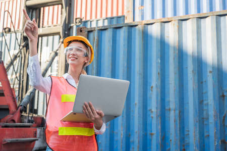 Foreman woman worker working checking at Container cargo harbor holding laptop computer to loading...