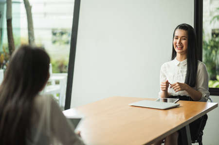 Beautiful two women Sit and work apart discussing with laptop and tablet on the table social...