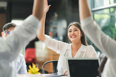 Asian business people raise their hands together.