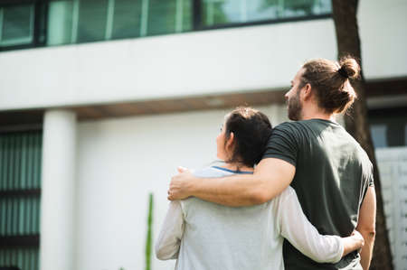 Husband and pregnant wife standing in front of and looking the house feeling happy. Insurance home family concept.の写真素材