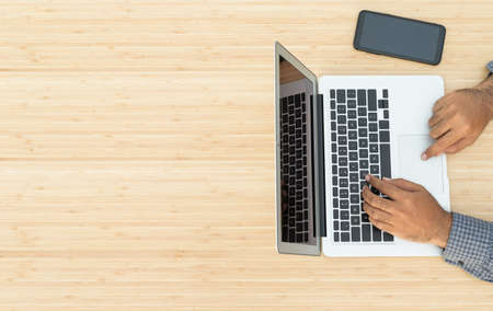 Top view of businessman typing keyboard using laptop of working project on the wooden table desk.の写真素材