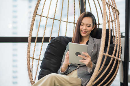Beautiful asian business woman using tablet working in office and smiling.