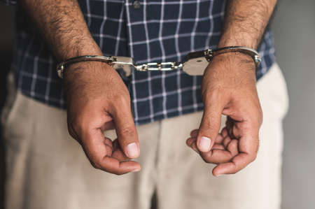 Prisoner man in jail with handcuffs. Close up Shackled in Hands.