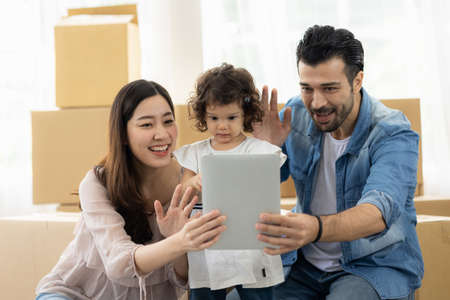 Family relaxing at home. Father mother and daughter using tablet watching movies, play game and...