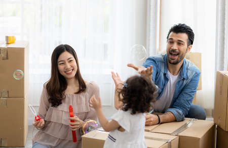Happy time family blow soap bubbles relax in living room. Everyone having fun in the house.の写真素材