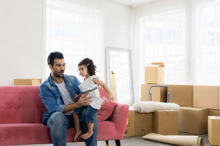 Happy family moment in the house. Father and daughter relaxing on red sofa. The family just moving in new house.の写真素材