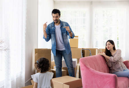 Happy family moment in the house. Father mother and daughter relaxing on red sofa. The family just moving in new house.の写真素材