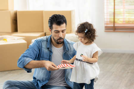 Happy moment family eating chocolate cookie in living room at home. Father and daughter laughing having a good meal in the morning.の写真素材