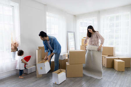 The family just moved to a new home. Arranging things to be arranged There are many parcel boxes. Parents and children have fun organizing things together.の写真素材