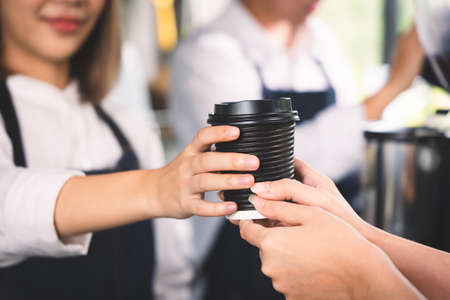 Close up hands customer receive the cup of hot coffee latte from barista. Coffee cafe shop beverage concept.の写真素材