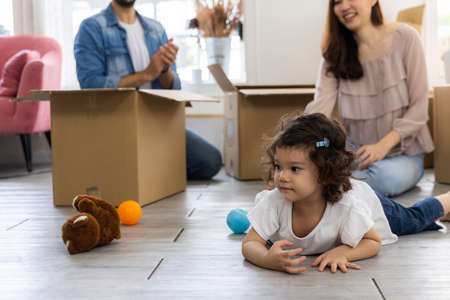 Cute daughter with parent. Happy family in living room. Moving new house a lot of parcel box. Father mother and daughter relax together at home.の写真素材