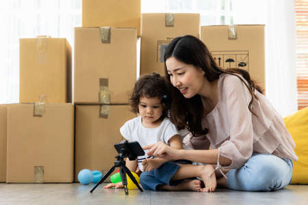 Family relaxing in living room at home. Mom and daughter smartphone watching movies, play game and video conference in the house. Digital Lifestyle Concept.の写真素材
