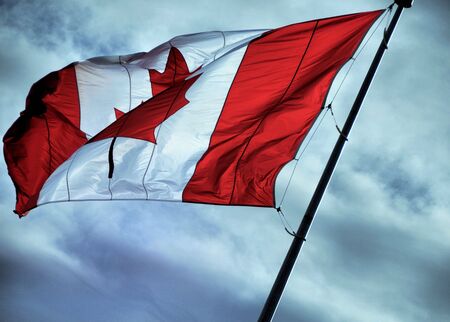 Canadian flag raised on a cloudy skyの写真素材