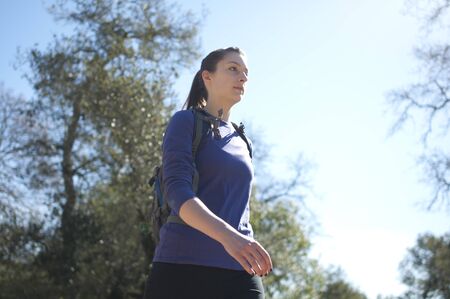 Centered close up of woman hiking in blue shirt facing right