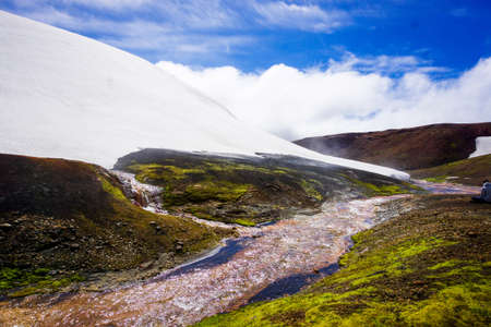 Misty river running through a mountain snowbankの写真素材