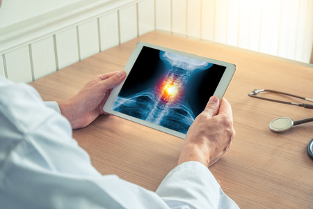 Doctor holding a x-ray of skeleton in medical office with stethoscope on the deskの写真素材