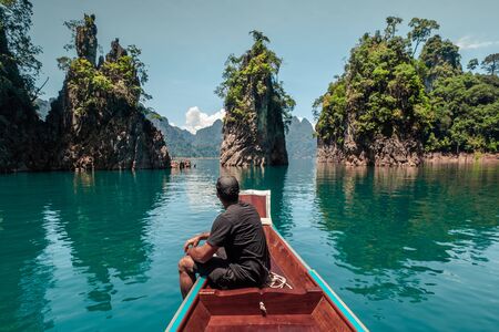 Tourist man sitting on a typical boat of thailand. Khao Sok National Parkの写真素材