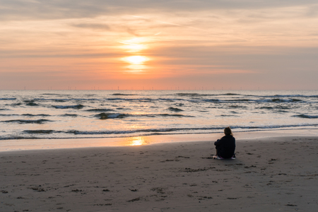 Egmond-aan-Zee, Netherlands, 09-24-2016: Girl at the seafront sunsetのeditorial素材