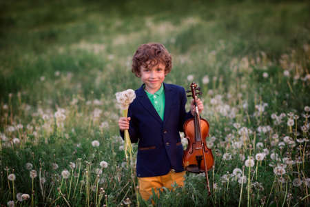 Curly-haired talented child plays the violin in natureの写真素材