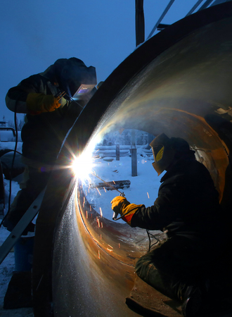 Two workers are welding inside and outside of the pipeの写真素材