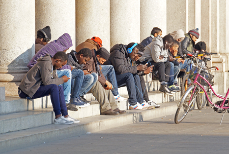 MILAN , ITALY - 25 December 2015 : People use mobile phones while sitting in the square .のeditorial素材